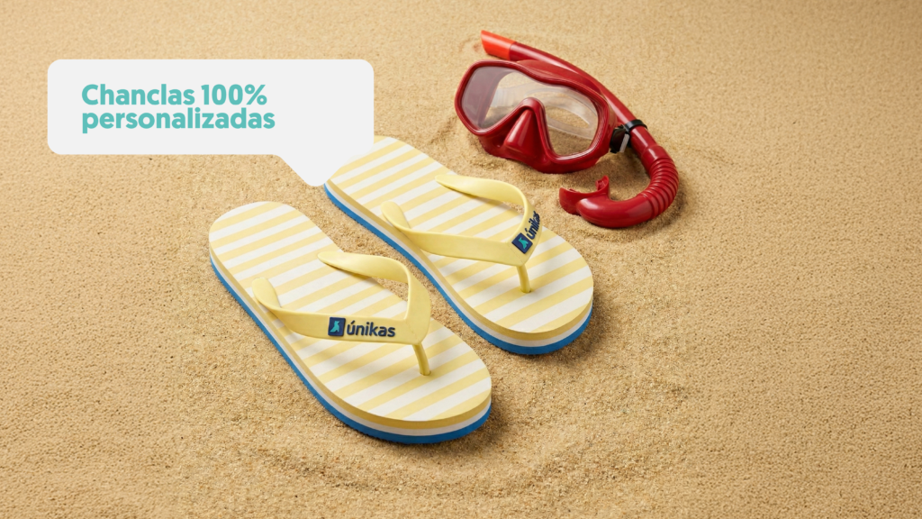 Chanclas personalizadas en la arena con unas gafas de buceo al lado y tubo de unikas