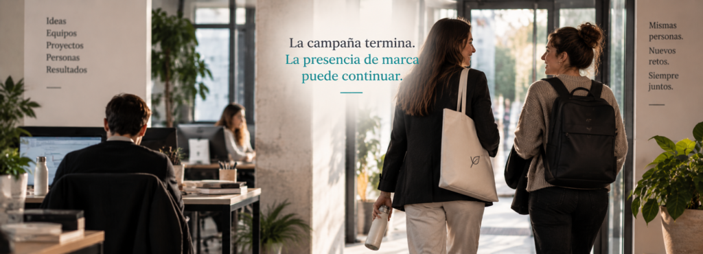 dos compañeras hablando tras finalizar su jornada laboral y llevan merchandising puesto y se ven más personas alrededor