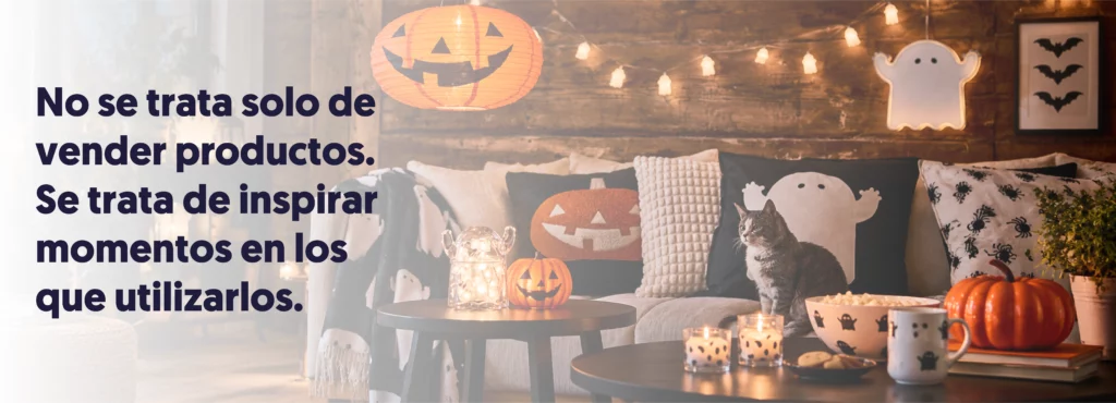 Salón decorado para Halloween con cojines de fantasmas y calabazas, velas, guirnaldas y un gato en el sofá